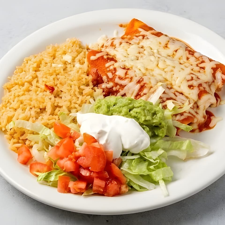 A plate of enchiladas with rice, lettuce, diced tomatoes, guacamole, and sour cream.